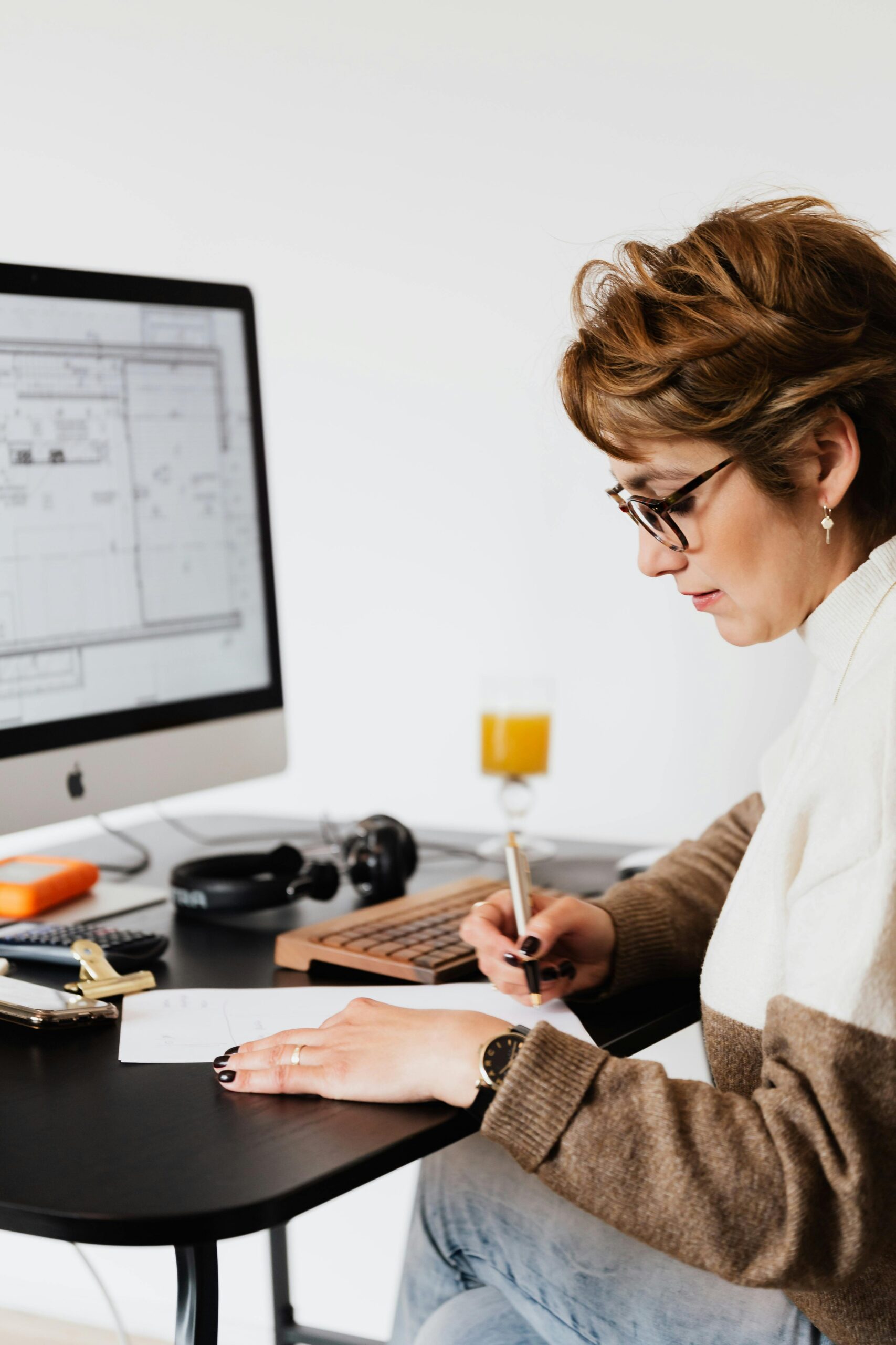 A woman in an office focused on analyzing data on her computer and taking notes.